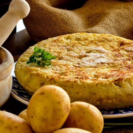 Spanish omelette with products to make it and a mortar